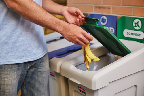 Throwing away a banana peel into a Slim Jim compost recycling bin