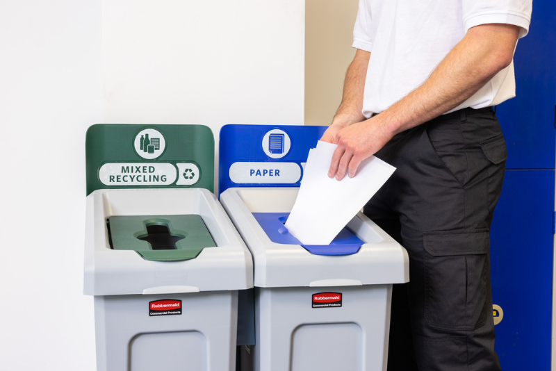 Person putting paper in Slim Jim Recycling Station